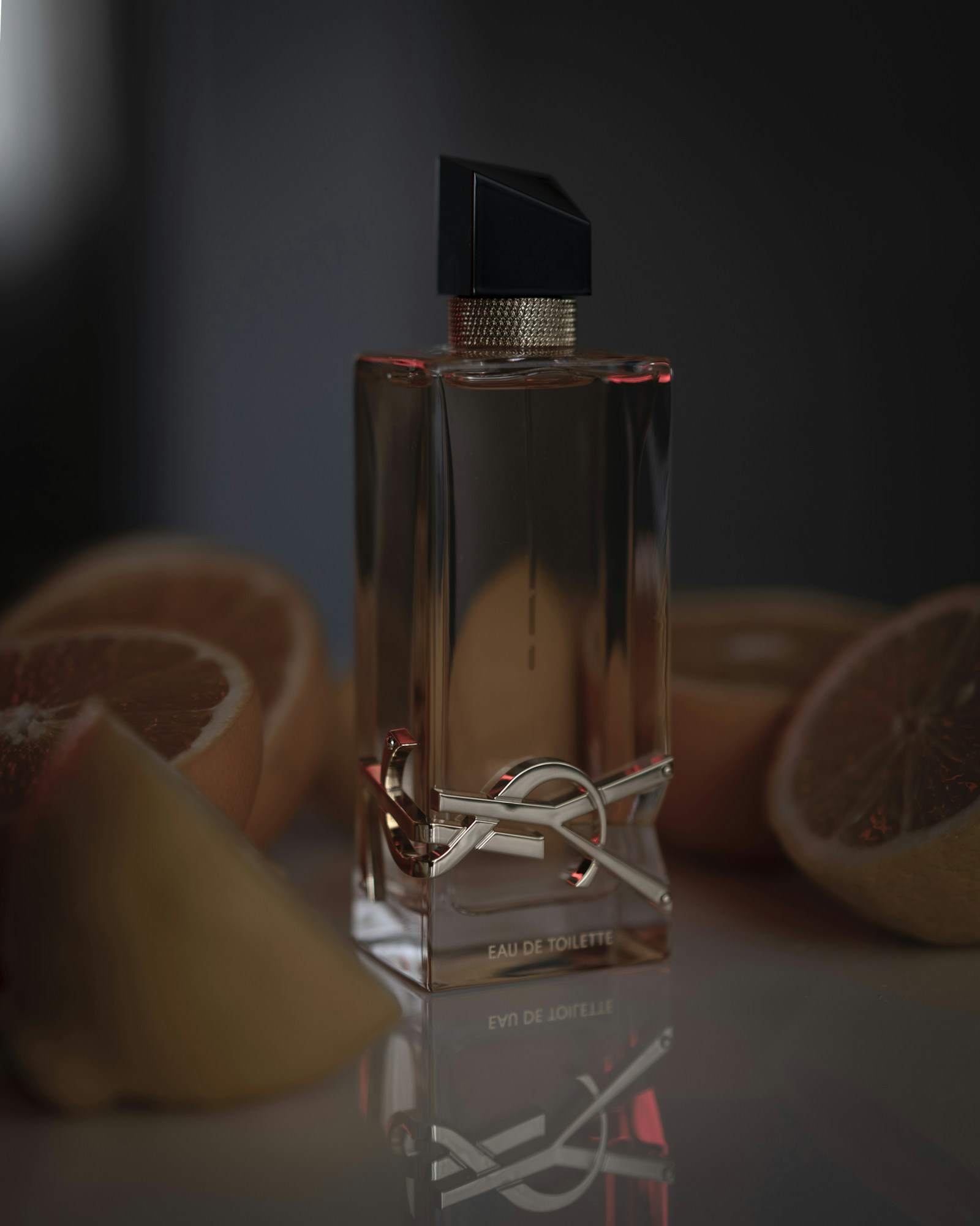 Perfume bottle styled with citrus in warm light